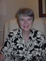 Portrait of Priscilla Huston, seated, in a patterned jacket.